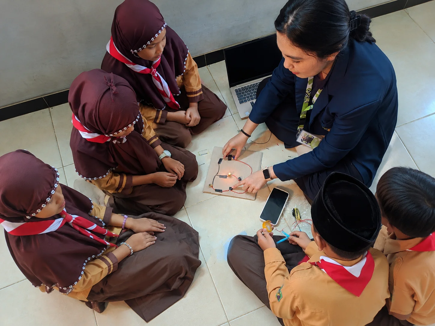 Mahasiswa FISIP Bakti Desa (FBD) Kelompok 56 Universitas Brawijaya mendampingi siswa kelas IV–VI MI Islamiyah Soso dalam kegiatan eksperimen membuat rangkaian listrik paralel sebagai bagian dari Program Generasi Emas pada rangkaian MATAMUDA Tahun Ajaran 2026/2027.