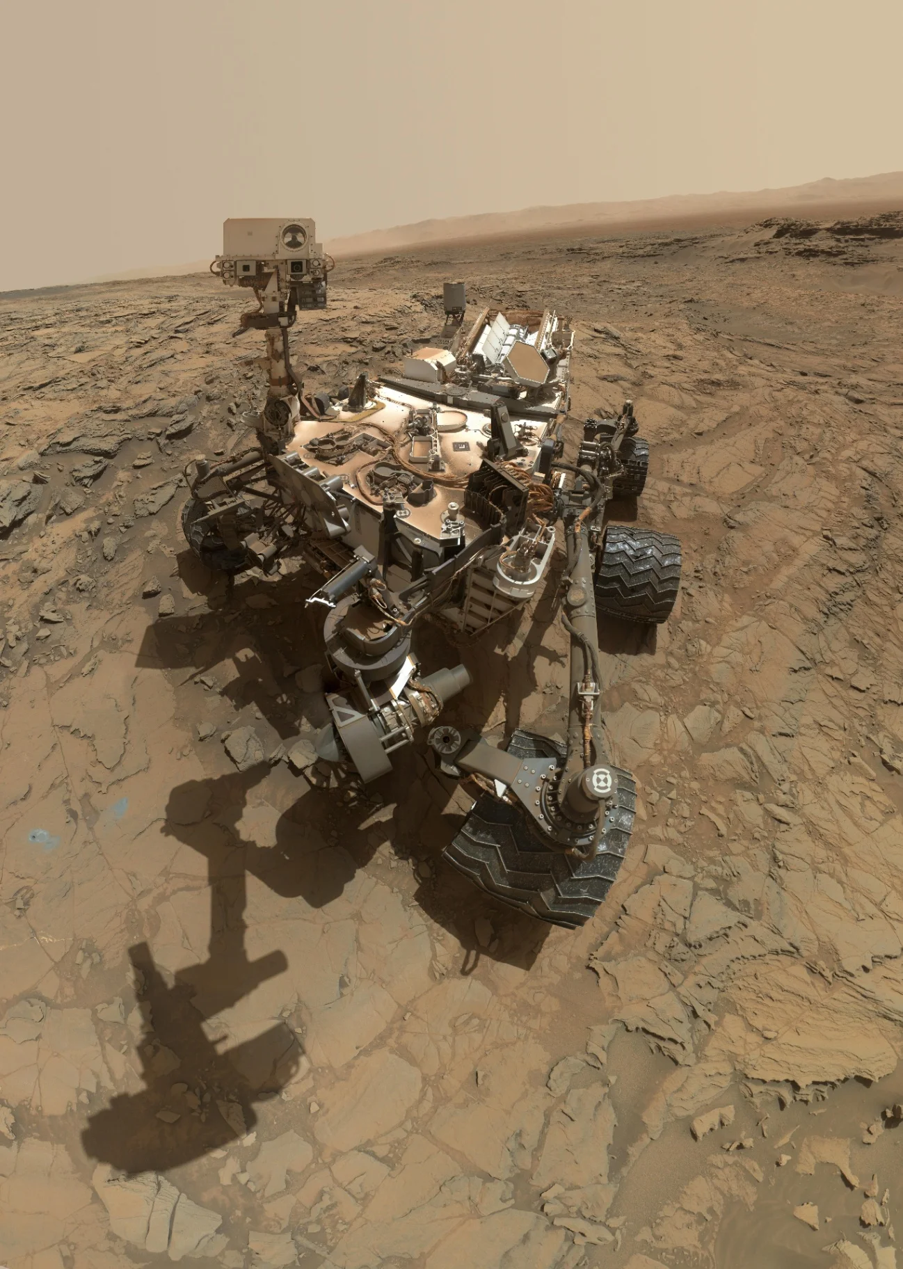 Permukaan Mars yang dipotret rover Curiosity di kawasan Gale Crater. Dataran berbatu dan tepi kawah terlihat dari lokasi pendaratan rover.